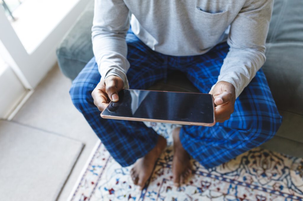 African american man using tablet and sitting on couch in living room