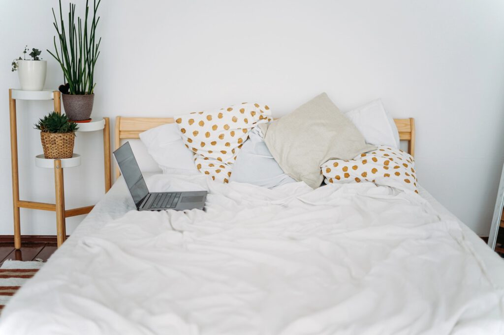 Opened laptop notebook on bed at bright scandinavian interior