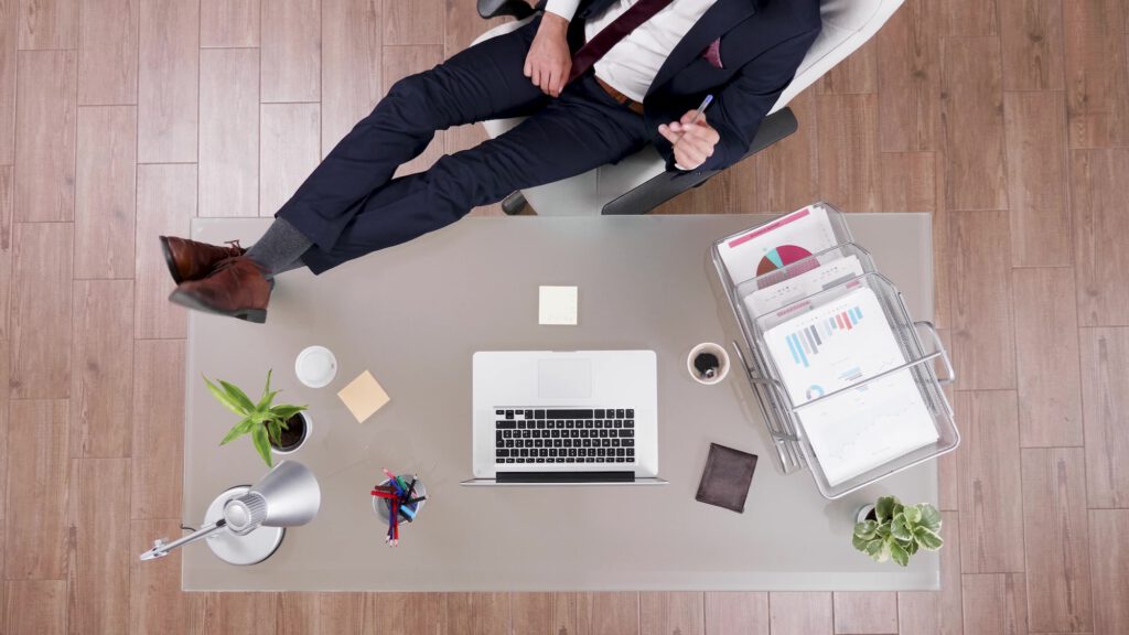 Top view of businessman in suit staying relaxed with feet on office desk